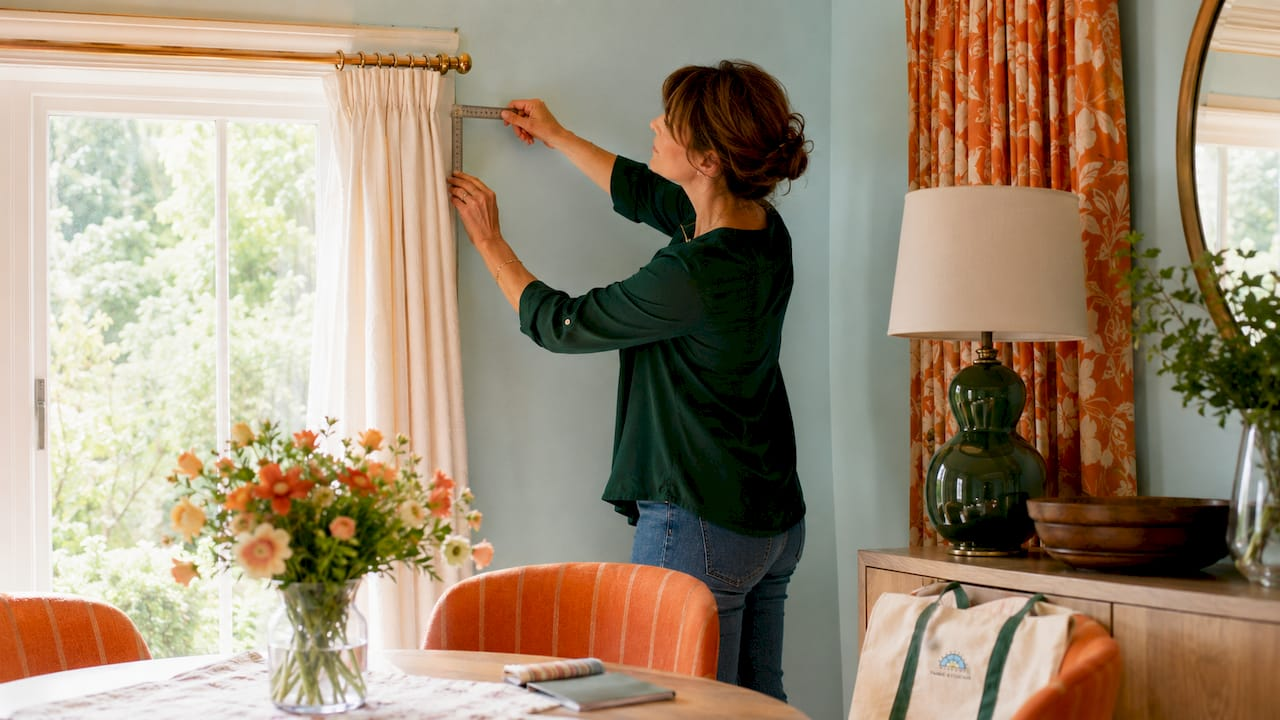 Woman measuring drapery return with metal ruler